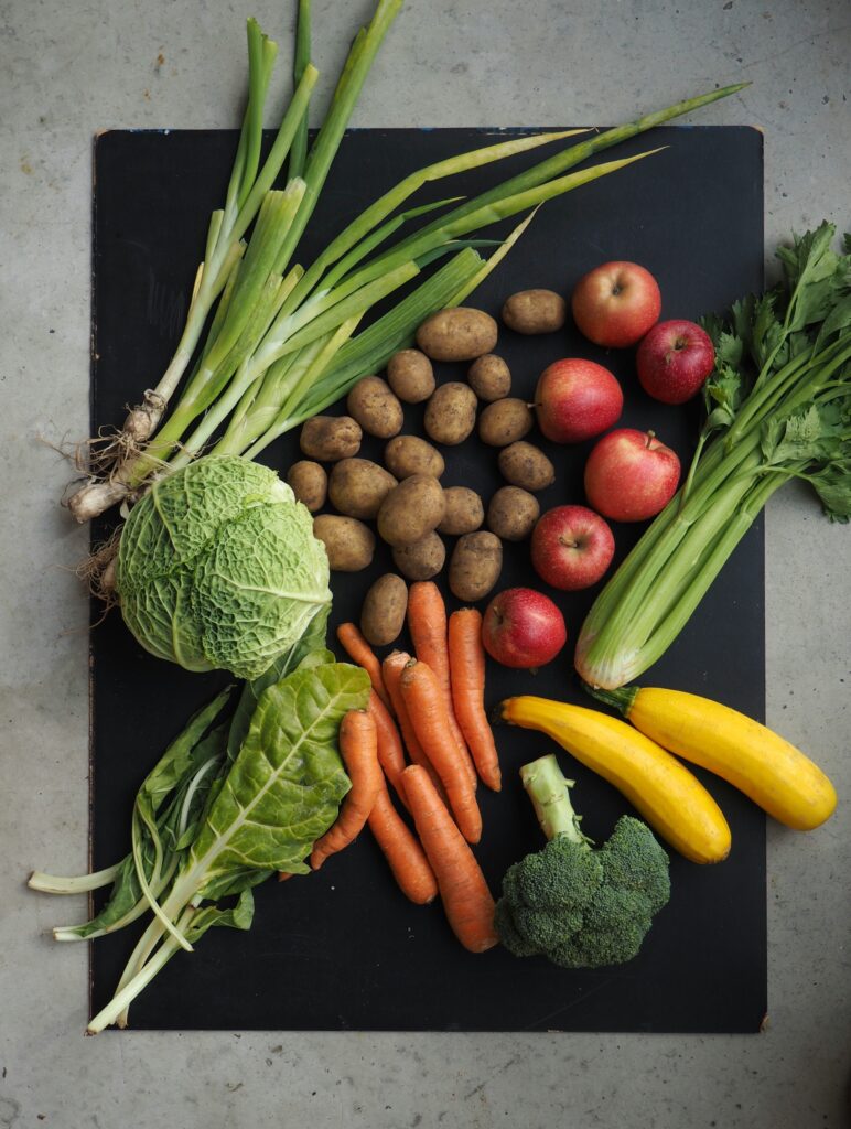 A food symptom journal next to a plate of fresh gut-friendly vegetables